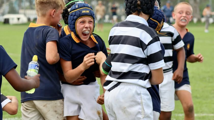 Young boys in rugby gear celebrating on field