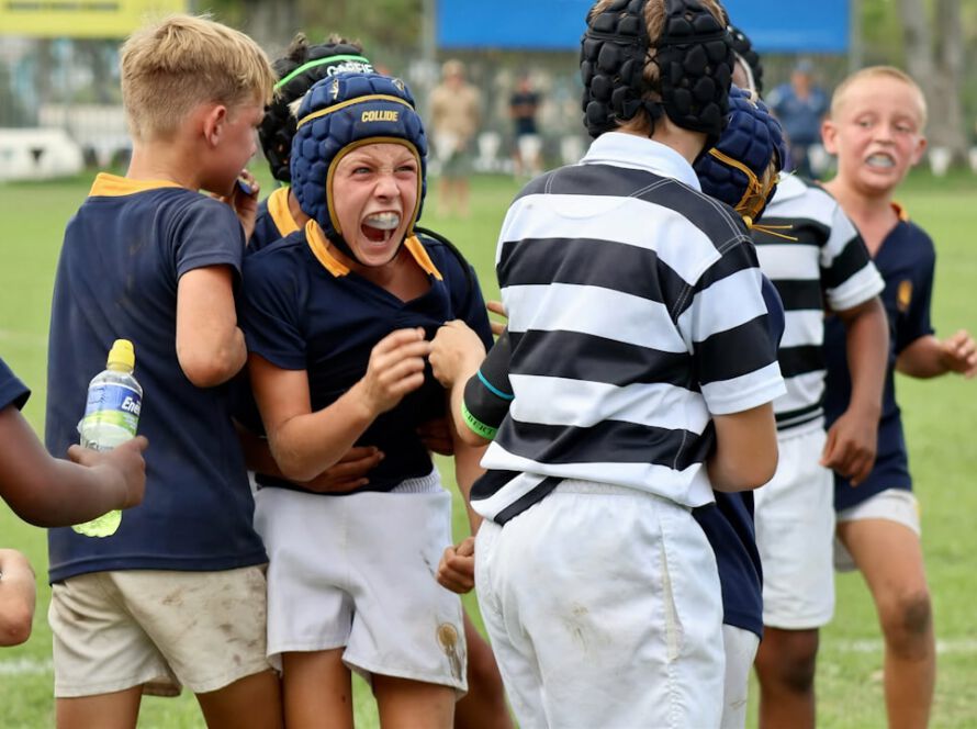 Young boys in rugby gear celebrating on field